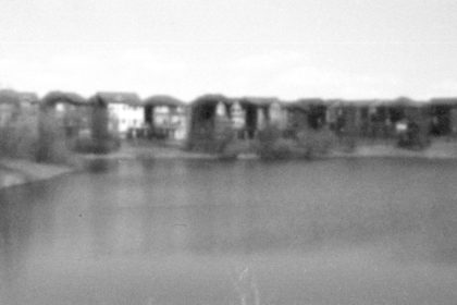 pinhole photo of houses by a pond