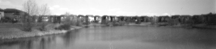 pinhole photo of houses by a pond