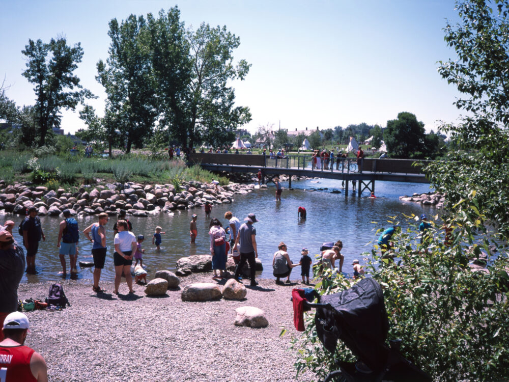 families play in the water at Calgary's St. Patrick's Island Park